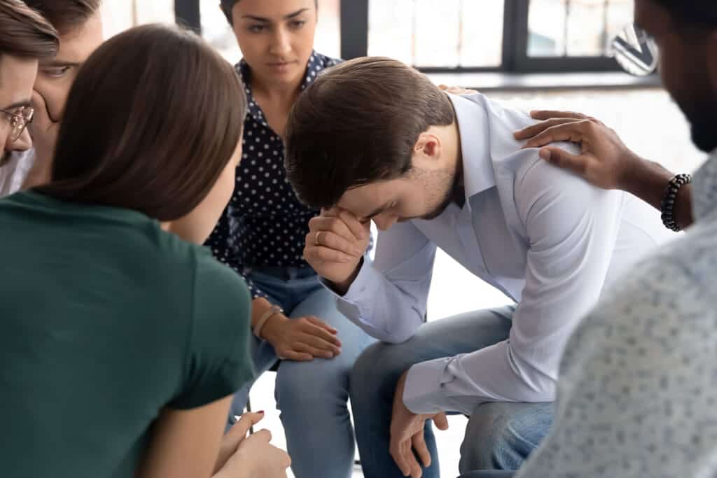 Person hides head while peers support him in a Chandler, AZ, IOP