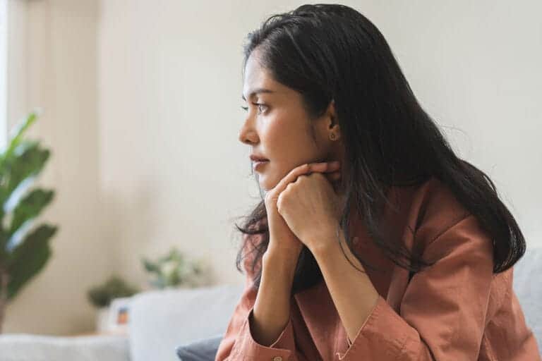 Woman sits on couch and wonders about reducing PTSD anxiety